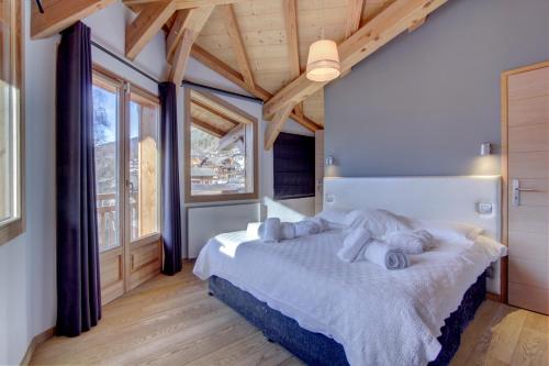 a bedroom with a large bed and large windows at Albatros in Morzine