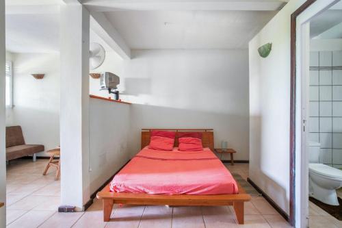 a bedroom with a bed with red sheets and a toilet at Appartement d'une chambre avec vue sur la mer jardin clos et wifi a Le Robert a 5 km de la plage in Le Robert