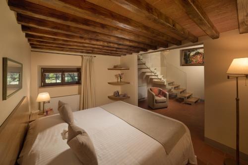 a bedroom with a white bed and a staircase at Villa La Casina in Castellina in Chianti