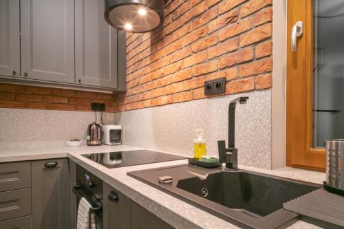 uma cozinha com um lavatório e uma parede de tijolos em Labo Apartment Metro Młociny em Varsóvia