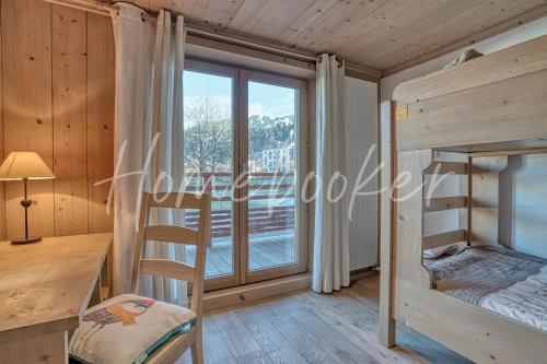 a room with two bunk beds and a desk and a window at Appartement Amour in Megève