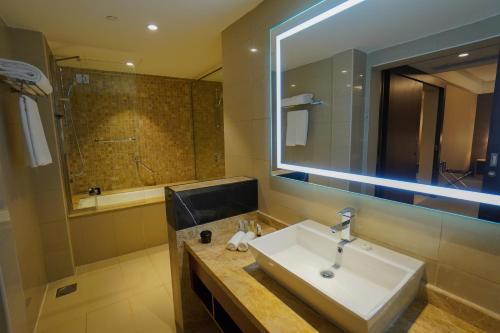 bagno con lavandino e grande specchio di The Grand Lux Hotel a Doha