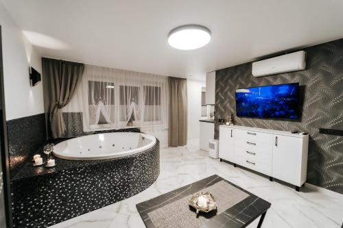 a bathroom with a tub and a tv on a wall at Kiss Apartment in Šilutė