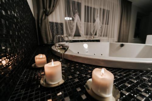 two candles and a glass of wine and a tub at Kiss Apartment in Šilutė