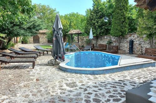 a swimming pool with an umbrella and tables and benches at VILLA GALATA in Varna City