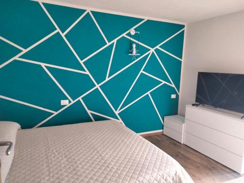 Dormitorio con pared azul, cama y TV en Green House 2.0, en Pieve di Teco