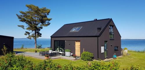 a black house with the ocean in the background at Stylish lake view house in Vadstena