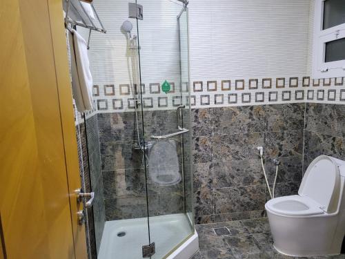 a bathroom with a toilet and a glass shower at Farah Hotel Apartment in Muscat