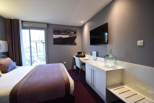 a hotel room with a bed and a desk and a television at Hôtel du Golf Saint Lazare in Limoges