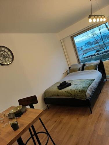a bedroom with a bed and a table and a window at Charmant studio - Gare colmar in Colmar