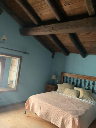 um quarto com uma cama com paredes azuis e uma janela em Los Diezmos em Jabaloyas