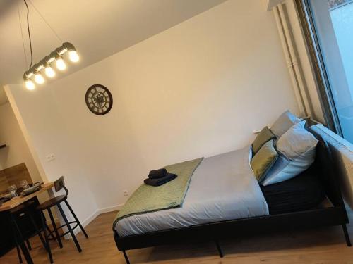 a bed in a room with a clock on the wall at Charmant studio - Gare colmar in Colmar