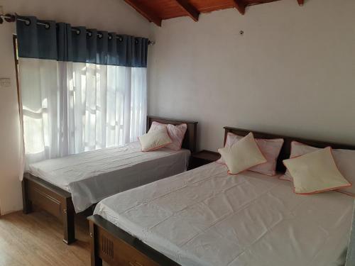 2 camas en una habitación con ventana en Mini Jungle Canopy Udawalawe, en Udawalawe