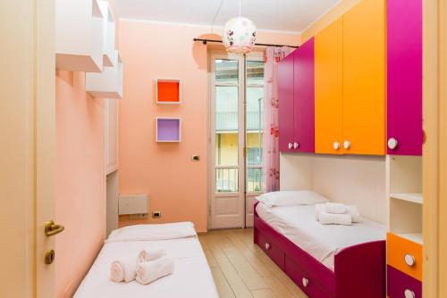 Alessandria Central Apt 10min walk Central Station في اليساندريا: سريرين في غرفة مع خزائن ملونة