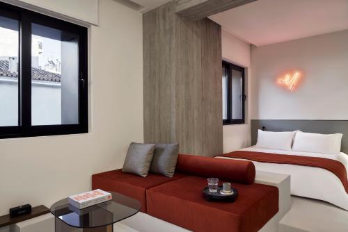 a bedroom with a bed and a red couch at The Newel Metaxourgeio in Athens