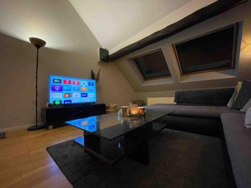 a living room with a couch and a table and a tv at Loft pour escapade en amoureux ou en famille. in Chaudfontaine