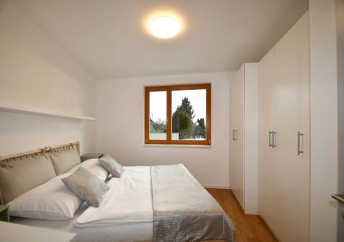 a white bedroom with a bed and a window at EFI Residence Holzova 28 in Brno