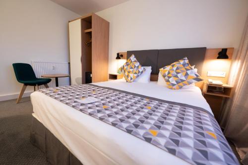 a bedroom with a large bed with a blue and yellow patterned bedspread at Holiday Inn Calais-Centre by IHG in Calais
