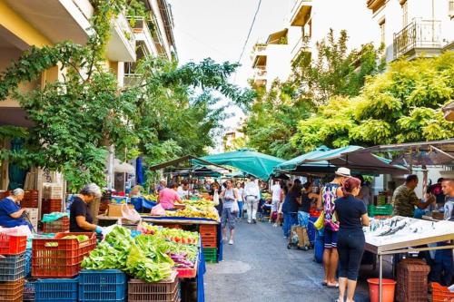 een groep mensen die rondlopen op een markt met groenten en fruit bij Little Chill in Athene