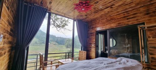 a bedroom with a bed and a large window at Bac Ha Threeland homestay in Bắc Hà