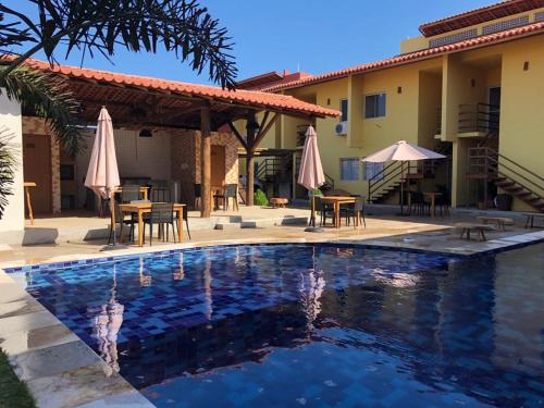 - une piscine avec des tables et des parasols à côté d'une maison dans l'établissement Apartamento em Luís Correia, à Luis Correia