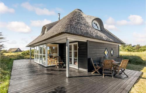 a thatched roof hut with a table and chairs on a deck at Holiday Home Lærkestien in Skagen