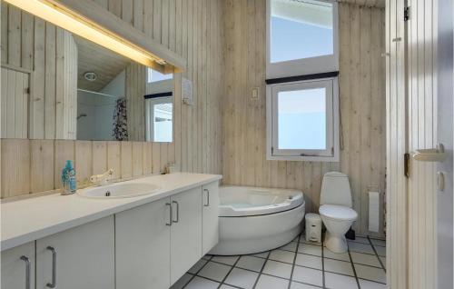 a bathroom with a tub and a sink and a toilet at 4 Bedroom Stunning Home In Hirtshals in Hirtshals