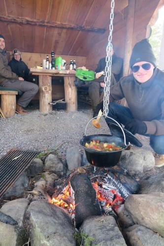 a man cooking food over a fire in a tent at Lovely house on beautiful private lakeside estate! in Bunn