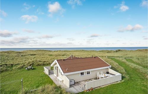 a cottage in a field with the ocean in the background at 2 Bedroom Nice Home In Hjørring in Hjørring
