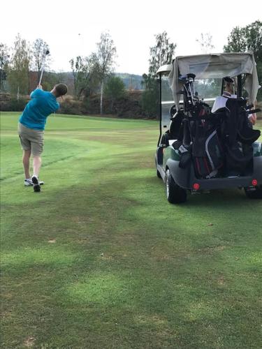 a man hitting a golf ball with a golf cart at Lovely house on beautiful private lakeside estate! in Bunn