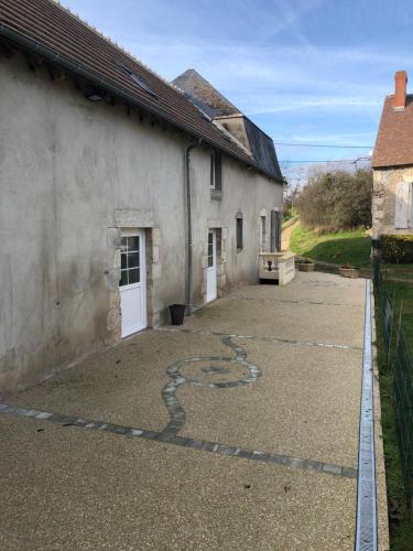 a driveway leading to a white building with a snake painted on it at Le champ des granges in Briare