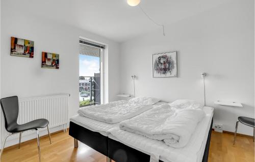 een witte slaapkamer met een bed en 2 stoelen bij Amazing Apartment In Rm With Kitchen in Rømø Kirkeby