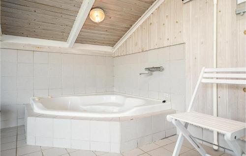 a white tub in a bathroom with a wooden ceiling at Amazing Home In Hjrring With 3 Bedrooms, Sauna And Private Swimming Pool in Lønstrup