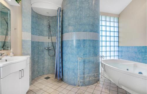 ein Bad mit einer Badewanne und einer Dusche mit blauen Fliesen in der Unterkunft Cozy Home In Hjrring With Sauna in Lønstrup