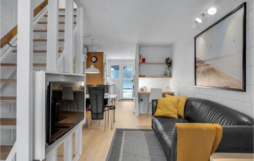 a living room with a black leather couch and a table at 2 Bedroom Cozy Apartment In Blokhus in Blokhus
