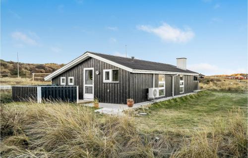 a small black house with a yard in front of it at Holiday Home Harrerenden Hjørring Iii in Lønstrup