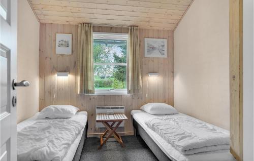 two beds in a small room with a window at 4 Bedroom Amazing Home In Hjrring in Lønstrup