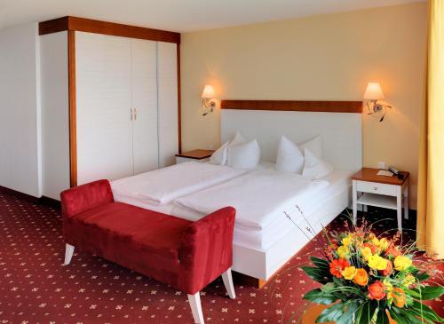 a bedroom with a white bed and a red chair at Hotel Fährhaus in Norddeich