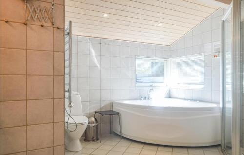 a white bathroom with a tub and a toilet at Gorgeous Home In Lkken With Sauna in Løkken