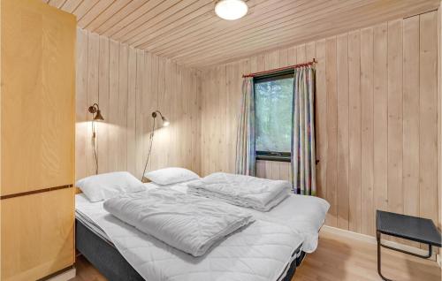 a bed in a wooden room with a window at Awesome Home In Blvand With 3 Bedrooms in Blåvand