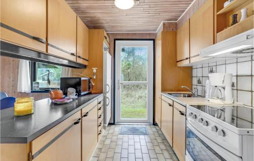 a kitchen with wooden cabinets and a large window at Holiday Home Østkrogen Blåvand X in Blåvand