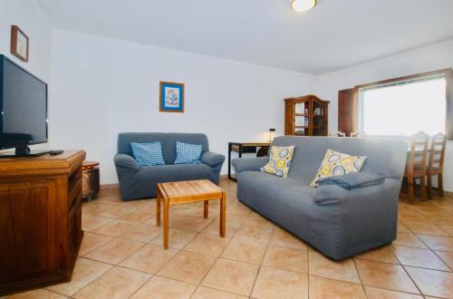 sala de estar con 2 sofás azules y TV de pantalla plana en Catarina House - Baleal Beach, Balcony, Pool, en Ferrel