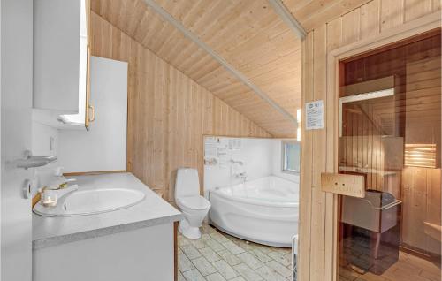 a bathroom with a tub and a toilet and a sink at Lovely Home In Ringkbing With Kitchen in Søndervig