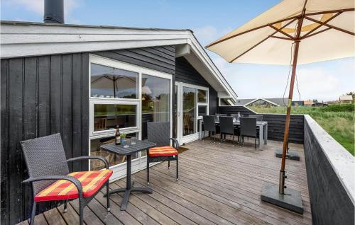 a deck with a table and chairs and an umbrella at Amazing Home In Hvide Sande With Wifi in Bjerregård