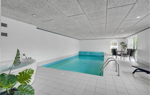 a swimming pool in a room with a tub and a table at Amazing Home In Blåvand With Kitchen in Ho
