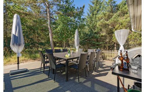 un tavolo con sedie e ombrelloni su un patio di Pet Friendly Home In Blåvand With Wifi a Blåvand