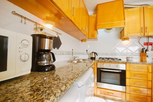 a kitchen with wooden cabinets and a coffee maker on the counter at Catarina House - Baleal Beach, Balcony, Pool in Ferrel