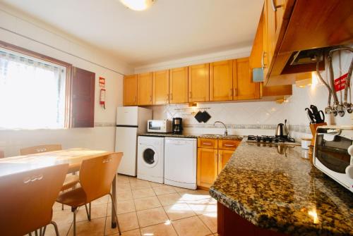 a kitchen with wooden cabinets and a counter top at Catarina House - Baleal Beach, Balcony, Pool in Ferrel