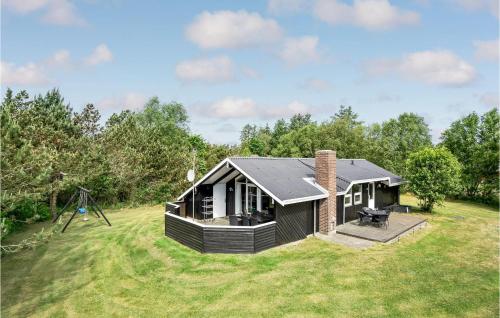 a small black house on a grass field at Holiday Home Gl Hovej X in Blåvand