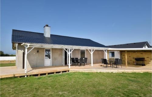 a house with a deck with chairs and a table at Awesome Home In Harboøre With Kitchen in Harboør